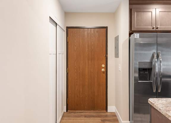 A kitchen with a wooden door and a fridge.
