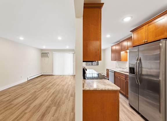 A kitchen with wooden cabinets and a stainless steel refrigerator.