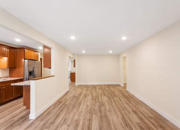 A spacious room with wooden flooring and a kitchen area with brown cabinets.
