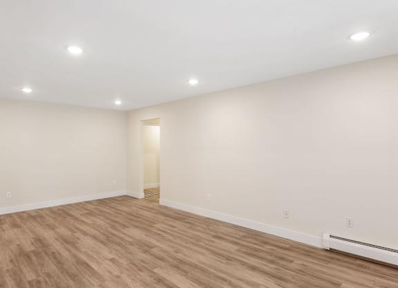 A room with wooden flooring and white walls.