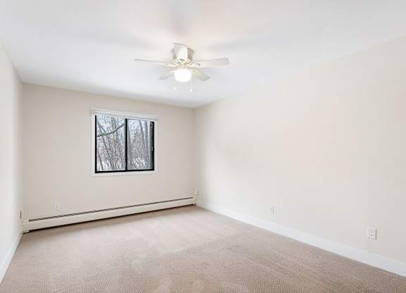 A room with a ceiling fan and a window.