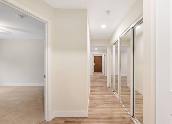 A long hallway with white walls and wood floors.