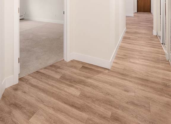A long hallway with wood floors and white walls.