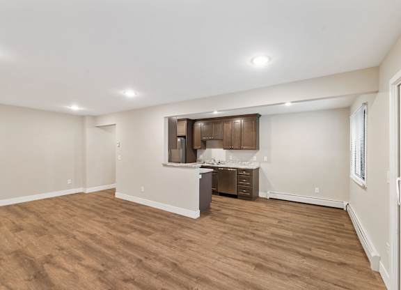 A spacious room with wooden flooring and a kitchenette in the corner.