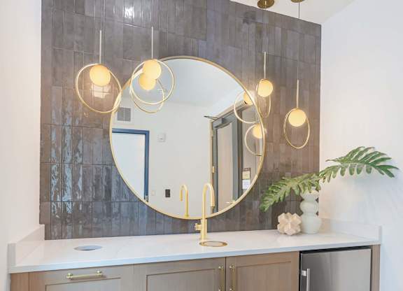 A bathroom vanity with a round mirror and lights above it.