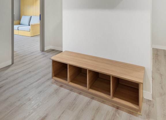 A room with a white wall and a wooden bench with drawers underneath it.