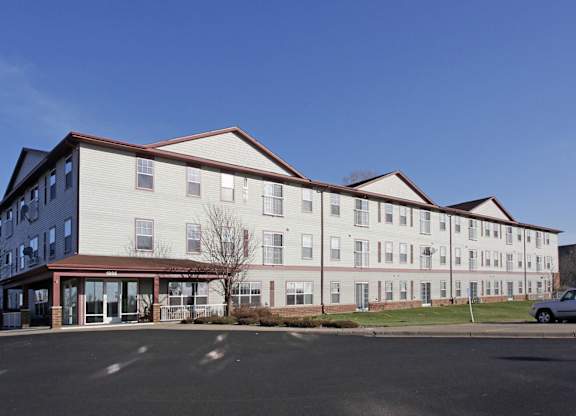 A large white building with a red roof and a parking lot in front.