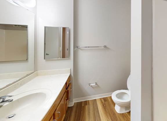 A white bathroom with a toilet, sink, and mirror.