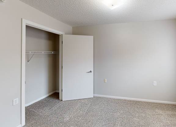 A room with a white door and a grey carpet.