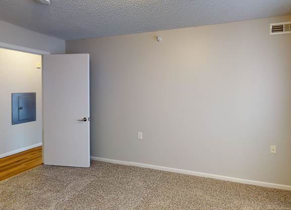 A room with a white door and a carpeted floor.
