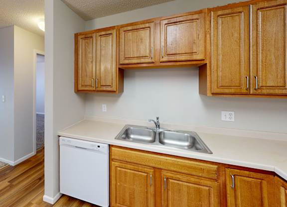 A kitchen with wooden cabinets and a white dishwasher.