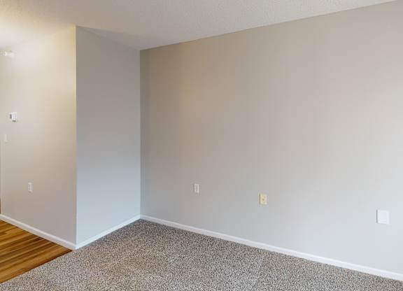 A room with a carpeted floor and a wall-mounted air conditioner unit.
