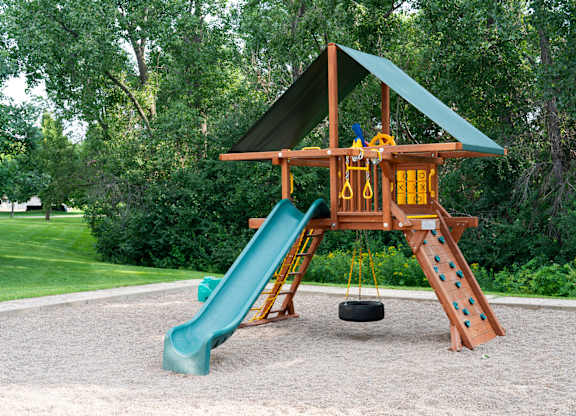 A playground with a green slide and a yellow and brown wooden structure.