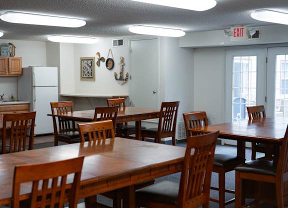 A room with a table and chairs and a refrigerator.
