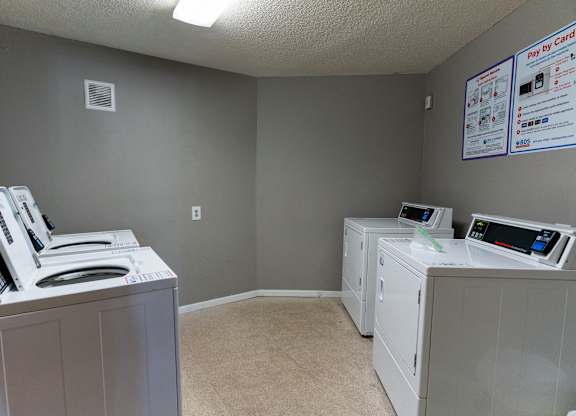 A room with two washing machines and a wall with flyers.