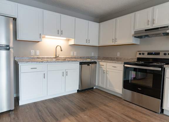 A kitchen with white cabinets and a stainless steel refrigerator.
