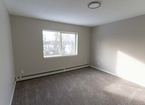 A room with a window and carpeted floor.