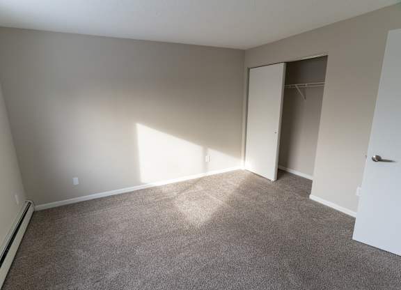 A room with a carpeted floor and a door leading to another room.