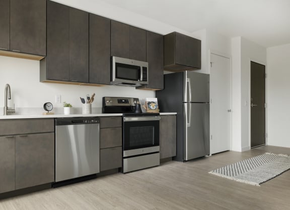 a kitchen with dark cabinets and stainless steel appliances