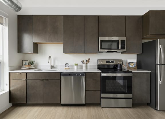 a kitchen with dark cabinets and stainless steel appliances