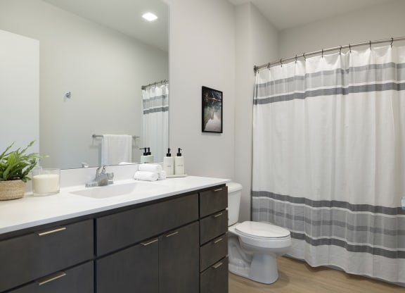 a bathroom with a toilet sink and shower in a 555 waverly unit