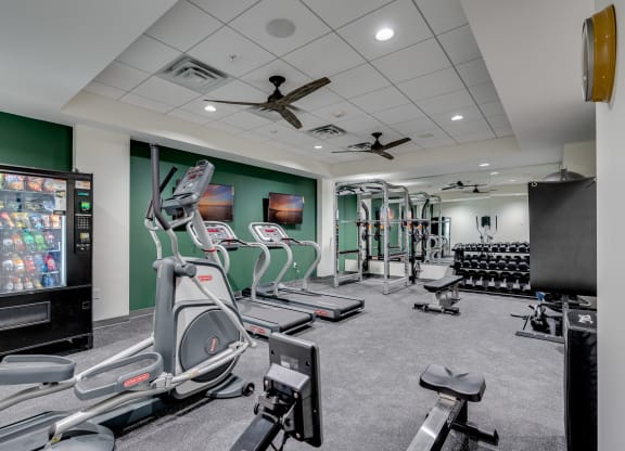 a gym with treadmills and other exercise equipment and a tv