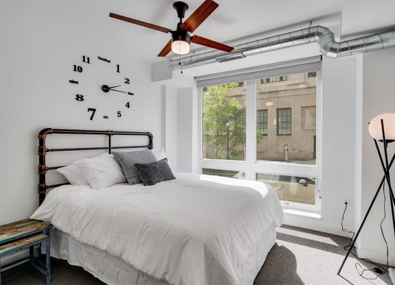 a bedroom with a large window and a bed and a ceiling fan