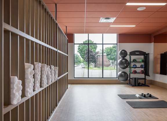 A gym with a row of shelves on the wall and exercise equipment.