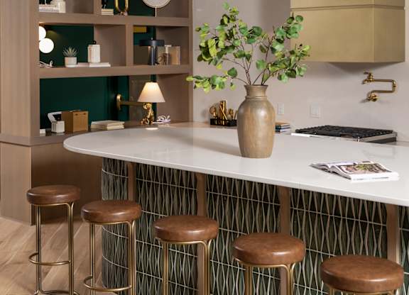 A kitchen with a white counter and brown stools.