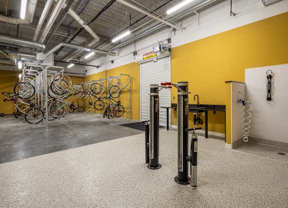 A bike repair shop with a yellow wall and bicycles hanging from the ceiling.