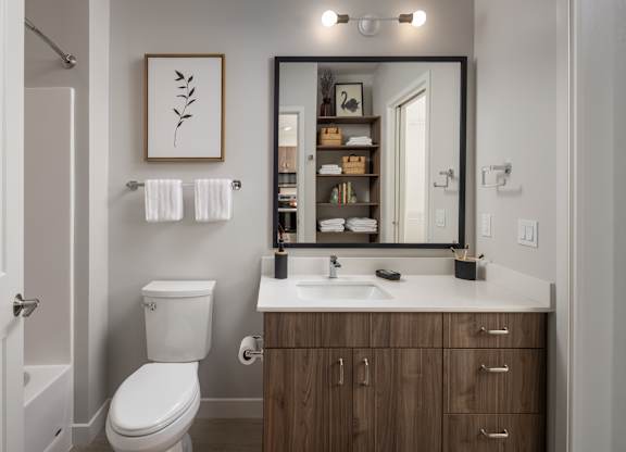 A bathroom with a white toilet and a mirror above a sink.