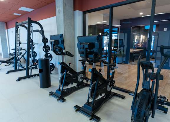 A gym with a variety of exercise equipment including treadmills, stationary bikes, and weight machines.
