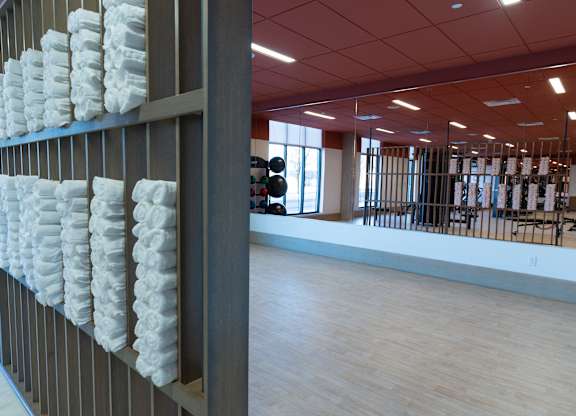 A wall of white towels hangs on a brown wall.