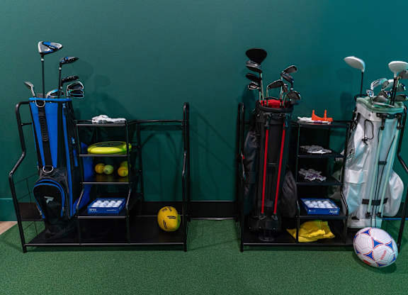 Two golf bags with clubs and a ball on the floor.
