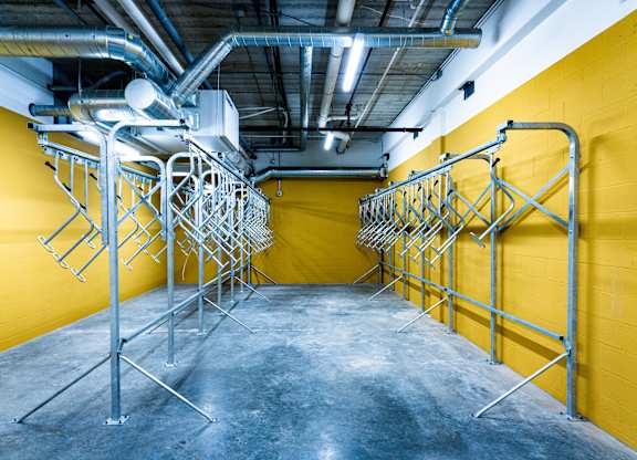 A room with yellow walls and a concrete floor has a metal rack system.