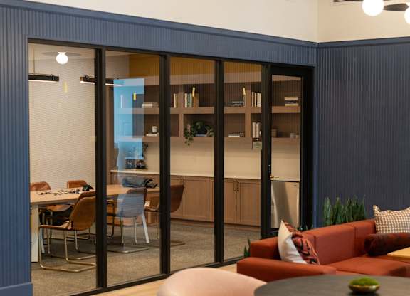 A modern living room with a glass door leading to a dining area.