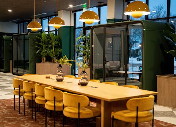 A conference room with a long table and yellow chairs.