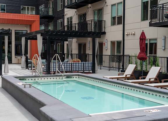 A pool area with a red umbrella and a black railing.