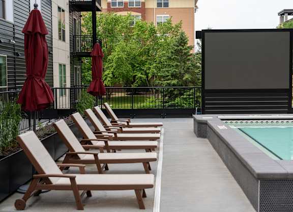 A poolside lounge area with chairs and a screen.