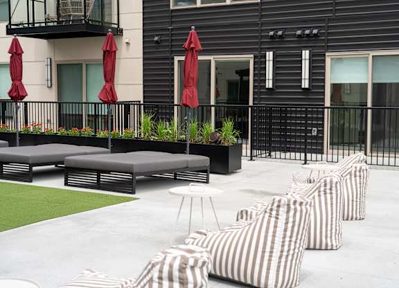 A patio with striped cushions and a black railing.