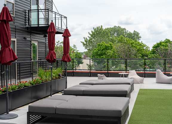 A patio with red umbrellas and grey couches.