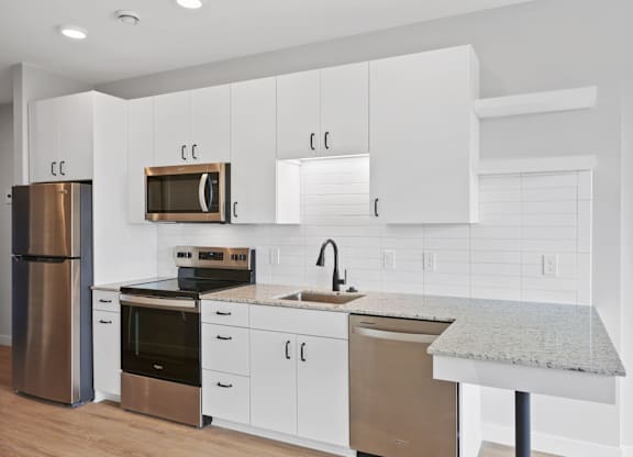 A kitchen with white cabinets and a granite counter.