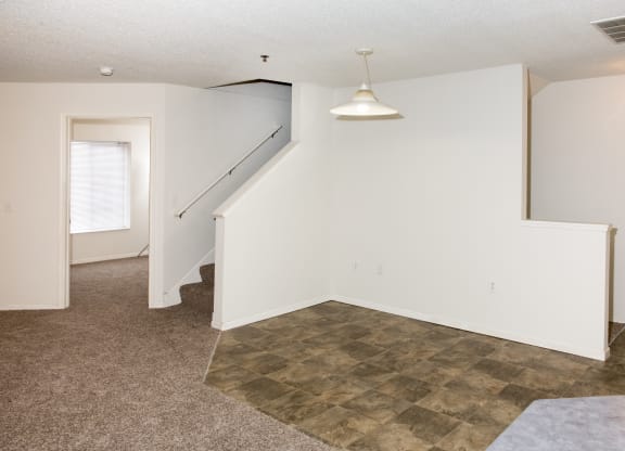 an empty living room with a staircase and white walls
