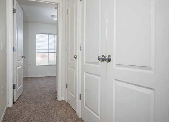 a bedroom with white doors and a carpeted floor and a window