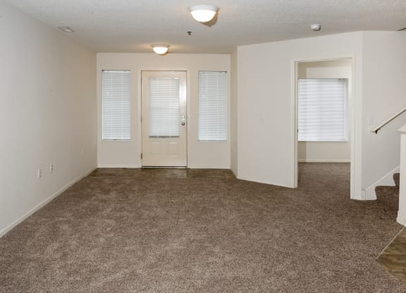 an empty living room with carpeting and white doors