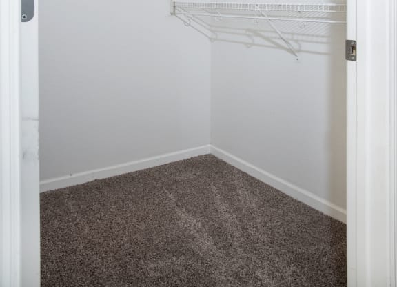 an empty closet with white shelves and white walls and carpet