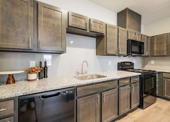 A kitchen with dark wood cabinets and black appliances.