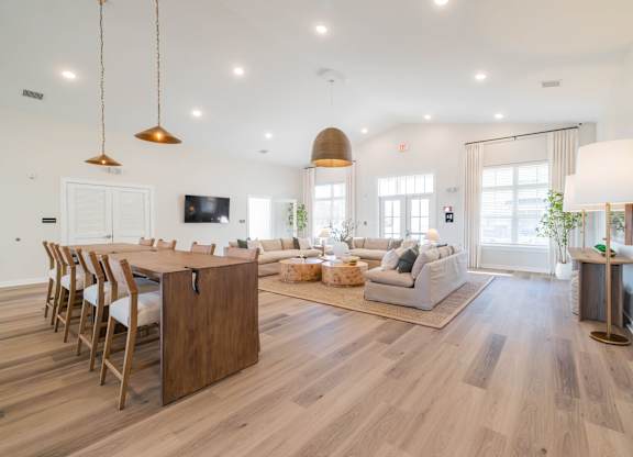 A well-lit, spacious living room with a dining area and a kitchen in the background.