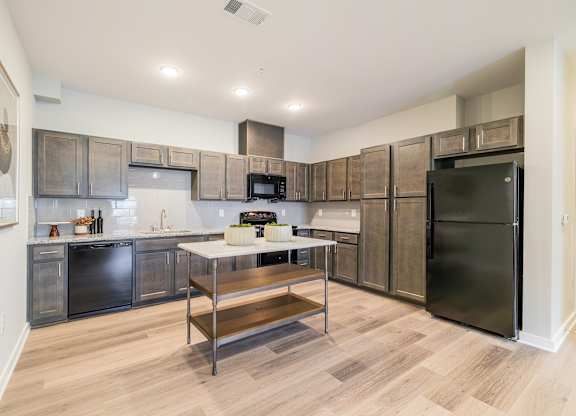A kitchen with black appliances and wooden cabinets.