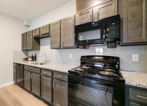 A black stove and microwave in a kitchen with wooden cabinets.